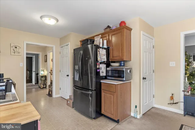 a living room with stainless steel appliances furniture refrigerator and cabinets