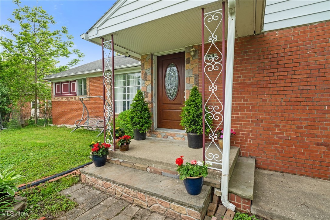 Property entrance featuring a lawn, a porch, and brick siding