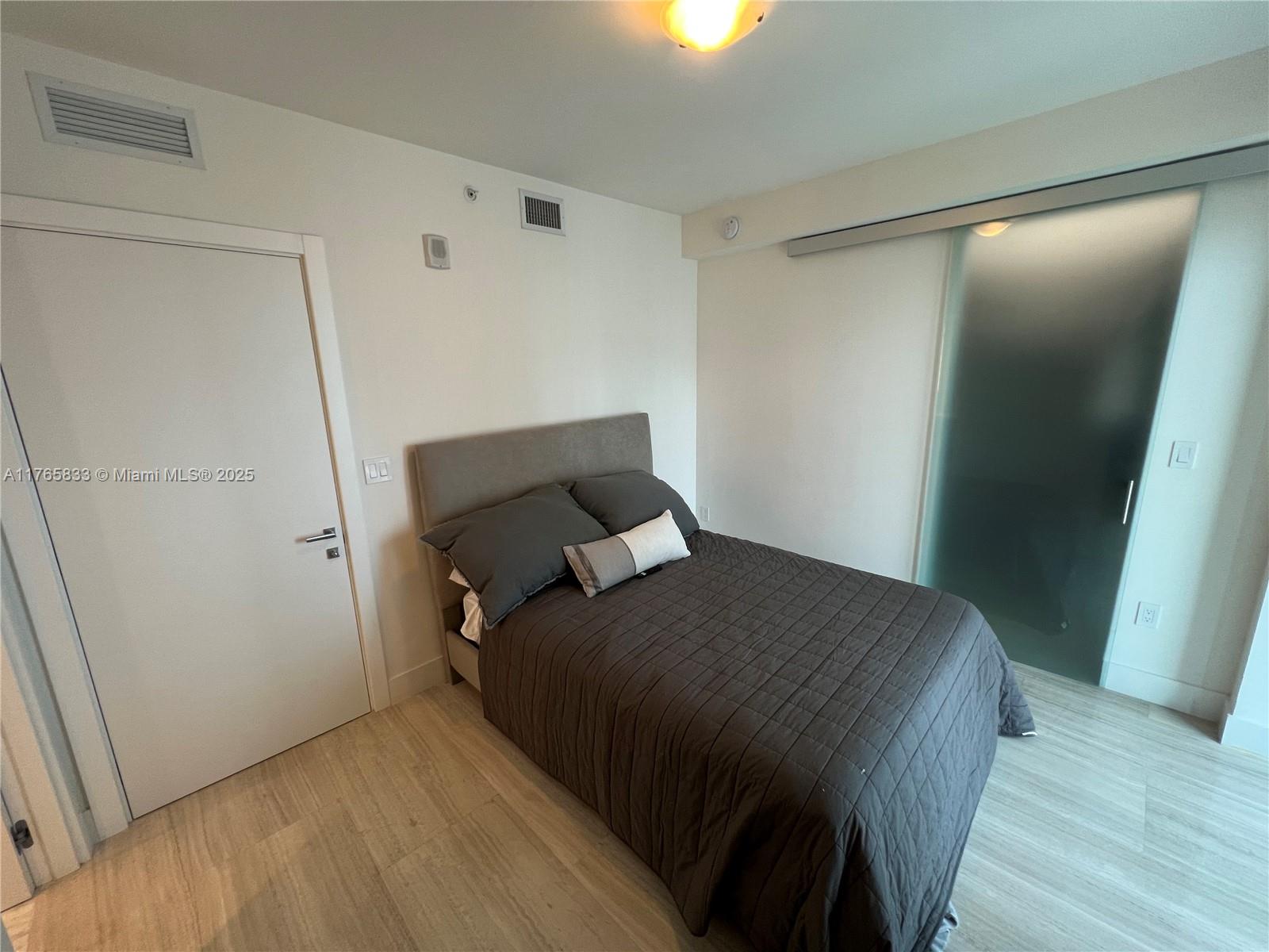 1451 Brickell Avenue, Unit 2004 Miami, FL 33131 - Photo 15 of 41 a bedroom with a bed and wooden floor