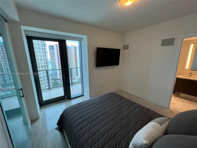 a bedroom with a bed and a flat tv screen next to a window