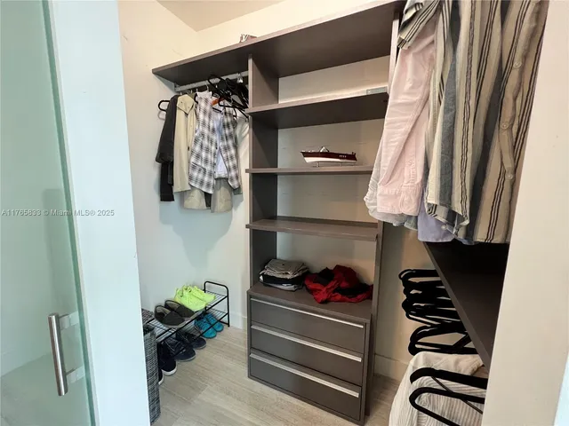 a view of walk in closet with clothes and shoes