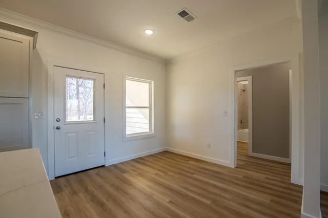 an empty room with wooden floor and windows
