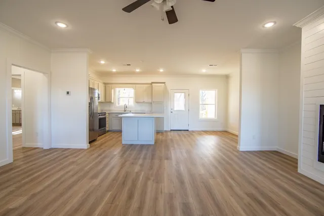 a view of kitchen and empty room with wooden floor