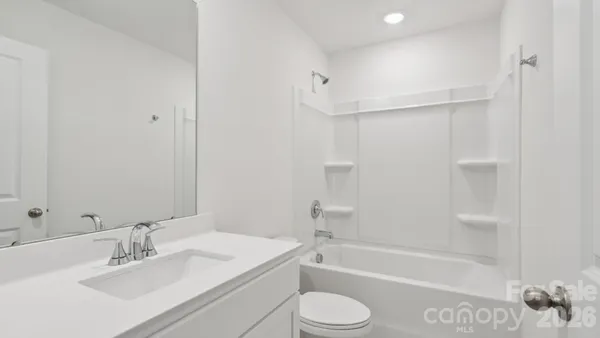 a bathroom with a bathtub shower sink vanity and toilet