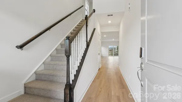 a view of staircase with lots of frames on wall and wooden floor