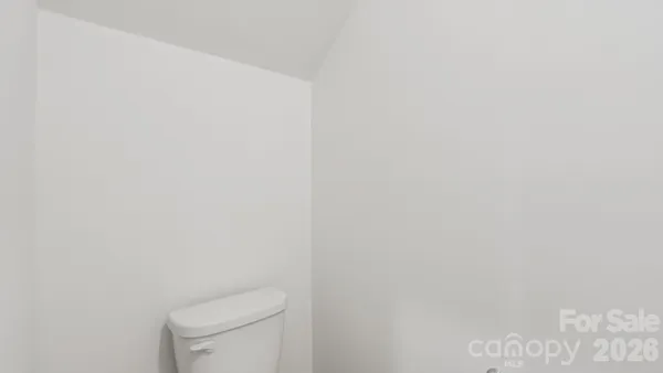a white toilet sitting next to a white wall