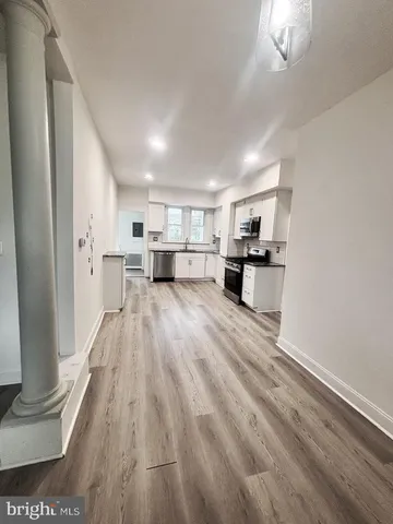a open kitchen with white cabinets and wooden floor