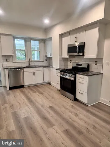 a large kitchen with stainless steel appliances granite countertop a stove a sink dishwasher and a microwave oven with cabinets