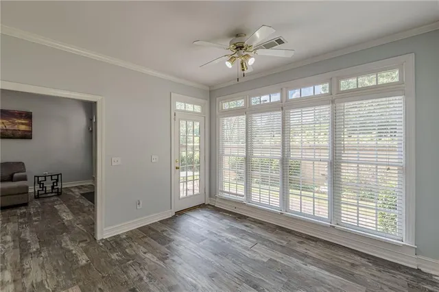 an empty room with wooden floor and windows
