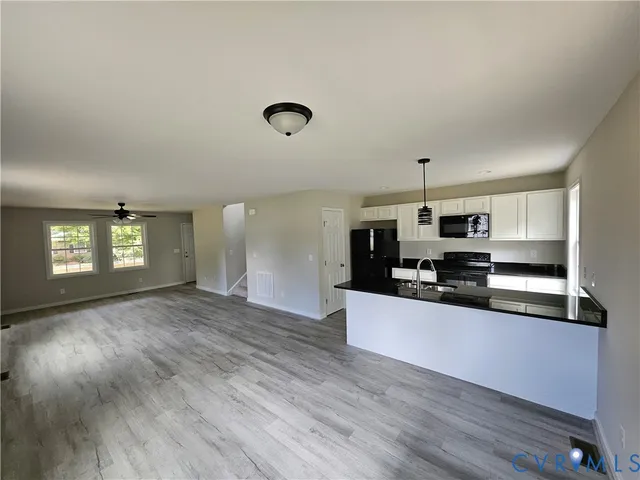 a large kitchen with stainless steel appliances a large counter top a stove and a wooden floors
