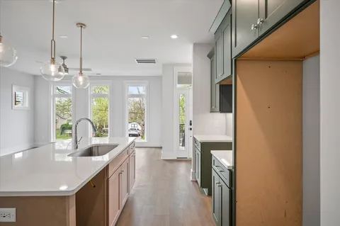 a kitchen with stainless steel appliances a refrigerator a sink dishwasher a oven with white cabinets and wooden floor