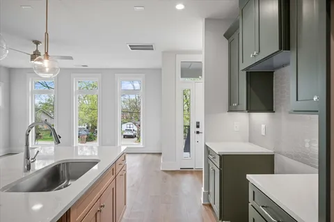 a kitchen with a sink and a refrigerator with wooden floor