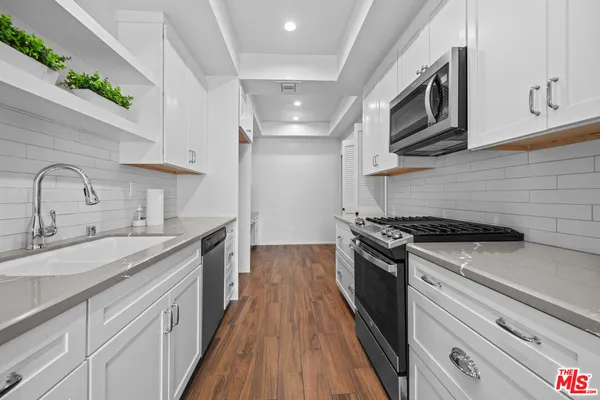 a kitchen with stainless steel appliances granite countertop a sink a stove top oven and cabinetry