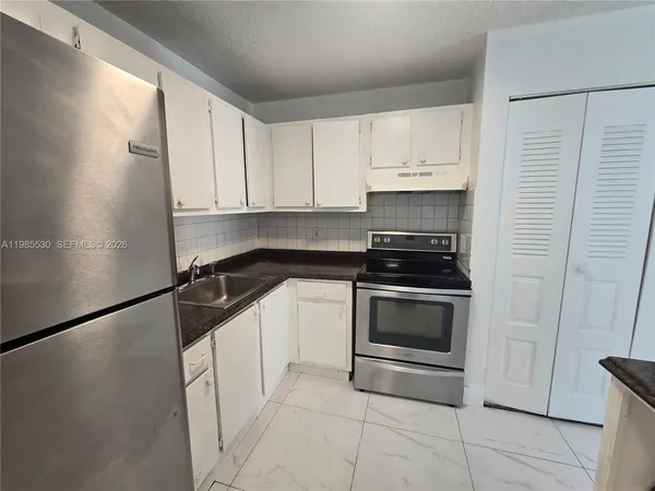 a kitchen with granite countertop white cabinets and black appliances
