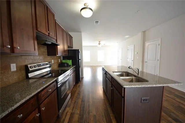 a kitchen with granite countertop a sink a counter space stainless steel appliances and cabinets