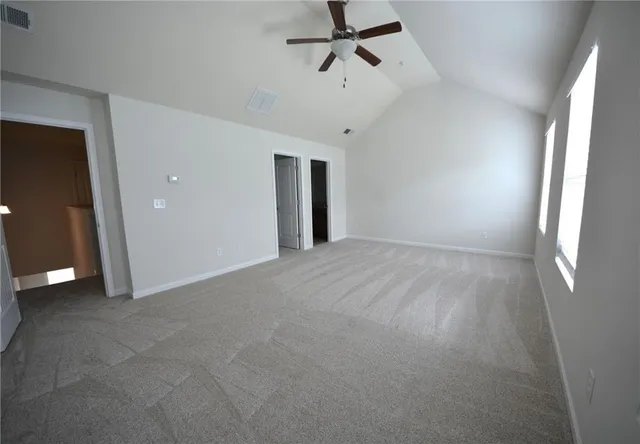 en empty room with windows and a ceiling fan