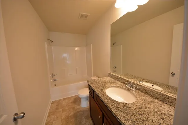 a bathroom with a granite countertop sink a mirror and a bathtub