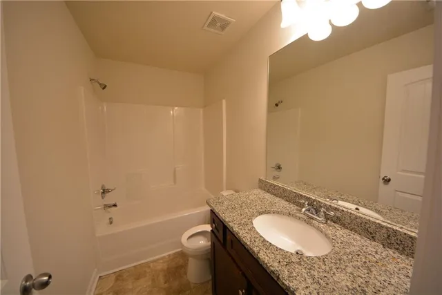 a bathroom with a granite countertop sink toilet mirror and bathtub