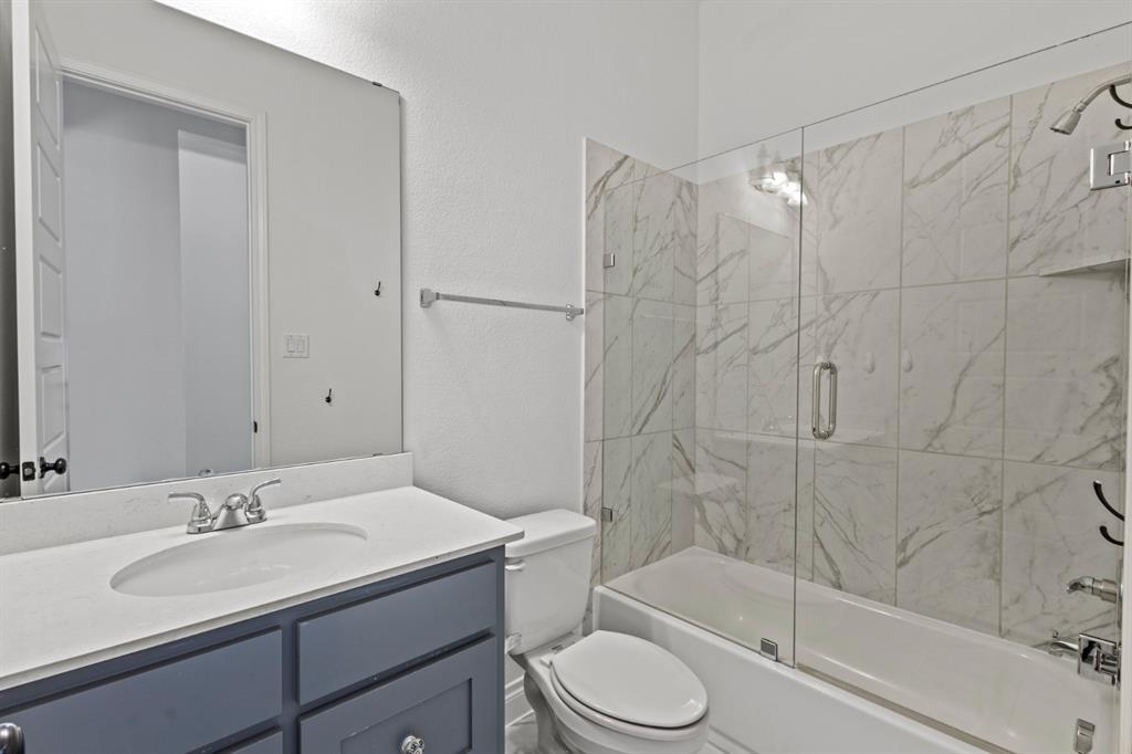 960 Knoxbridge Road Forney, TX 75126 - Photo 8 of 22 Bathroom featuring a tub-shower combination with a clear glass enclosure and large-format tile surround