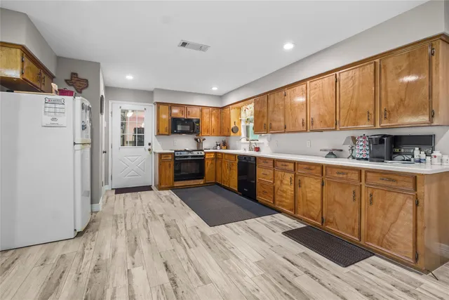 a kitchen with stainless steel appliances granite countertop a refrigerator a sink dishwasher a stove with wooden cabinets and floor