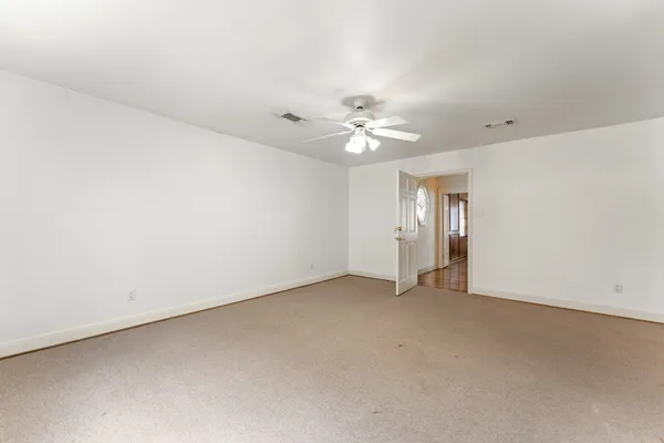 an empty room with chandelier fan and closet area
