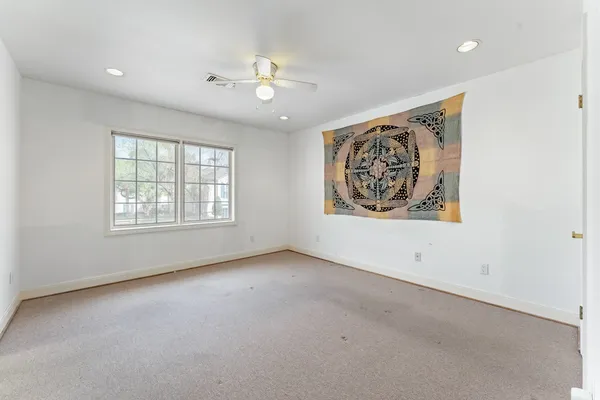 an empty room with windows and chandelier fan