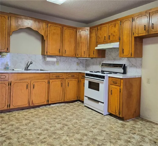 a kitchen with stainless steel appliances granite countertop a stove a sink dishwasher and a refrigerator