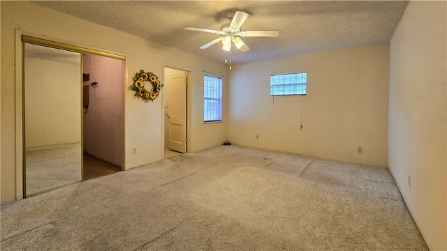 an empty room with windows and ceiling fan