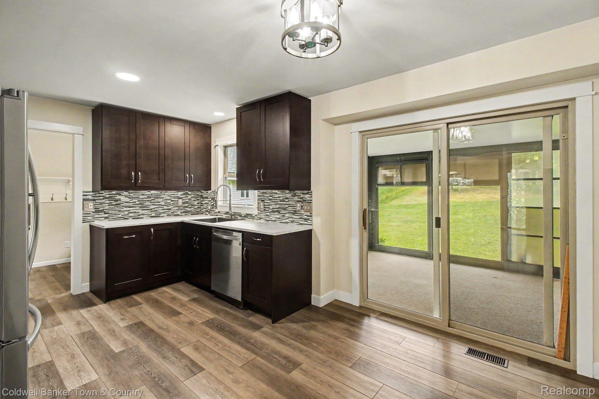 332 Triangle Lake Road Howell, MI 48843 - Photo 7 of 27 Modern kitchen featuring dark wood cabinetry, light countertops, and a mosaic tile backsplash