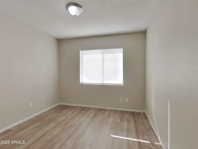 a view of an empty room with wooden floor and closet