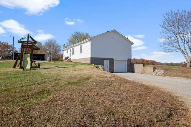 a view of house with backyard and trees in the background