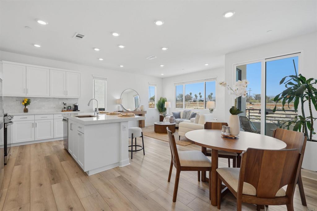 2402 Cascalote Loop San Diego, CA 92154 - Photo 3 of 35 a kitchen with a table chairs stove and white cabinets