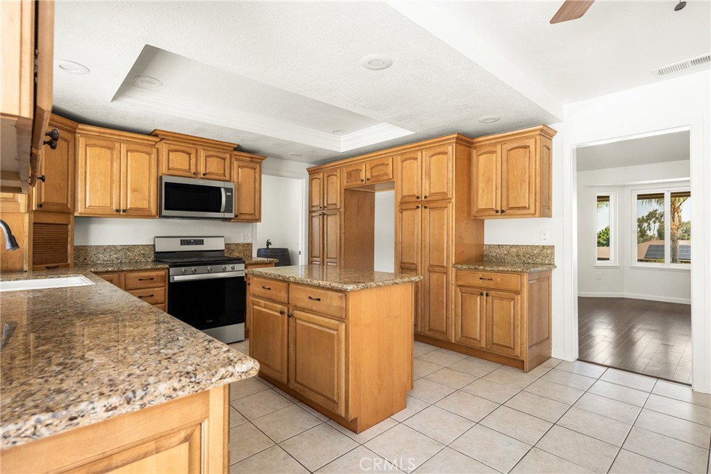 16481 Valle Vista Way Riverside, CA 92506 - Photo 17 of 73 a kitchen with stainless steel appliances granite countertop a stove top oven a sink dishwasher and a refrigerator with wooden floor
