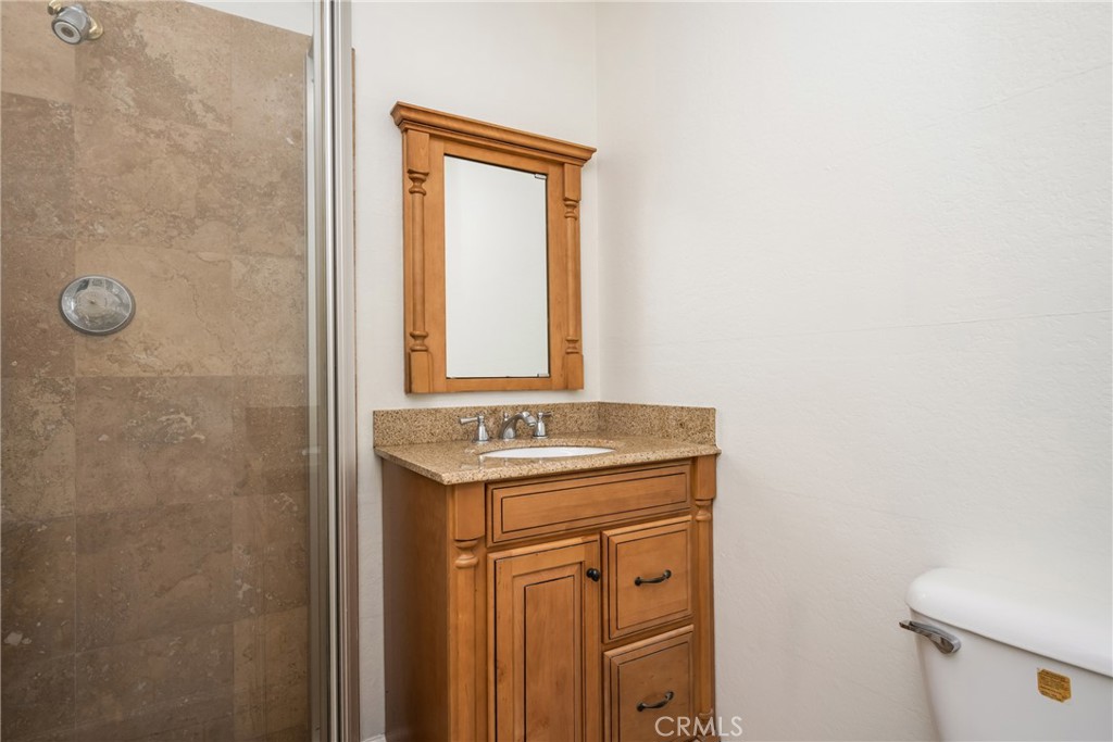16481 Valle Vista Way Riverside, CA 92506 - Photo 22 of 73 a bathroom with a granite countertop sink a toilet and a mirror