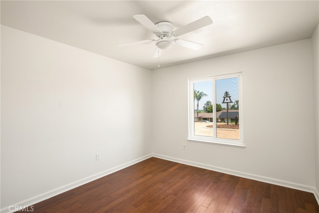 16481 Valle Vista Way Riverside, CA 92506 - Photo 36 of 73 an empty room with wooden floor ceiling fan and windows
