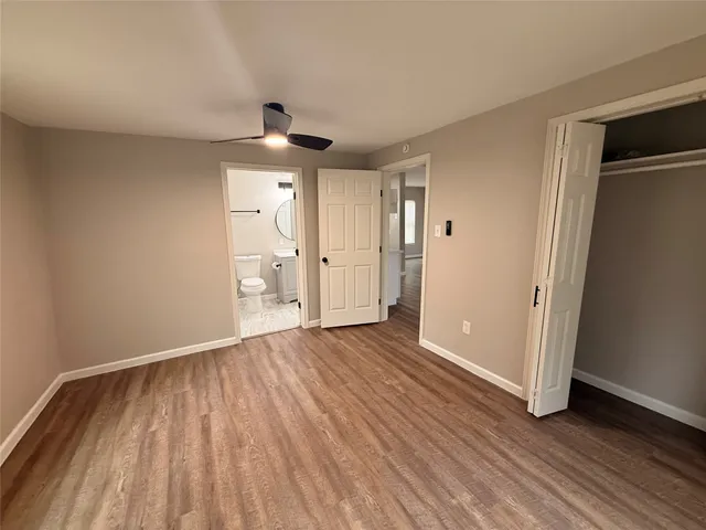 a view of an empty room with wooden floor cabinet and a window