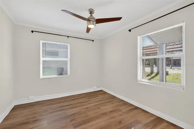 a view of an empty room with wooden floor and a window