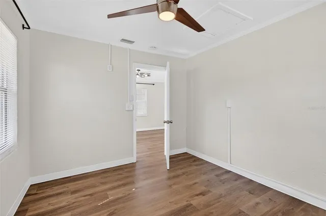 an empty room with wooden floor ceiling fan and windows