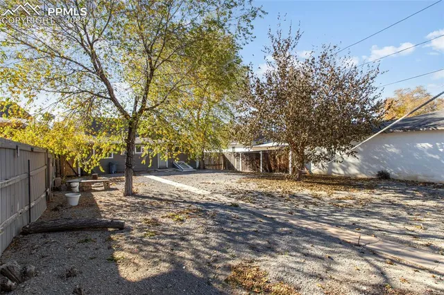 a backyard of a house with large trees and outdoor seating