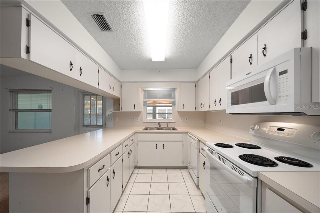 8431 Southwest 93rd Place, Unit A Ocala, FL 34481 - Photo 27 of 56 a kitchen with granite countertop a sink a stove and cabinets