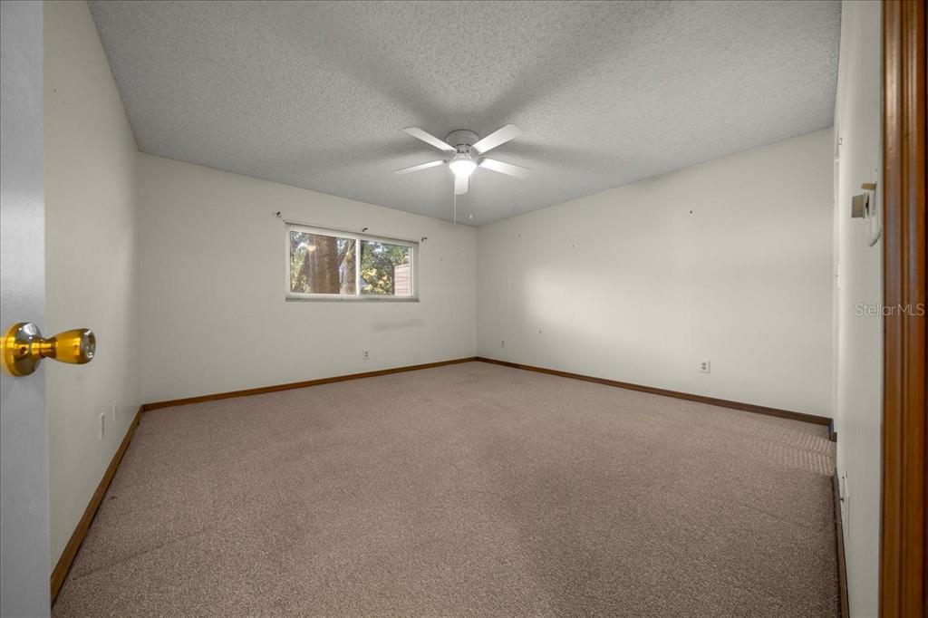 8431 Southwest 93rd Place, Unit A Ocala, FL 34481 - Photo 45 of 56 an empty room with a window and chandelier fan
