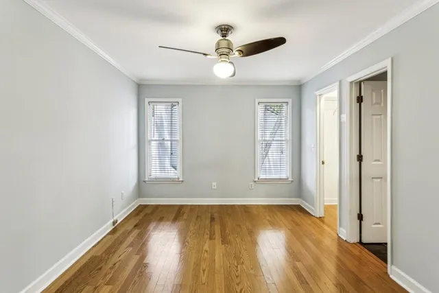 a view of empty room with wooden floor and fan