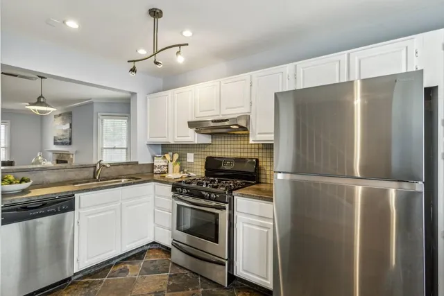 a kitchen with stainless steel appliances a refrigerator sink and white cabinets