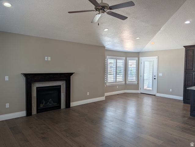 171 South Mustang Road East Grantsville, UT 84029 - Photo 4 of 41 Spacious living area featuring wood-finish flooring, a dark wood mantel fireplace with tile surround, and multiple windows with plantation shutters