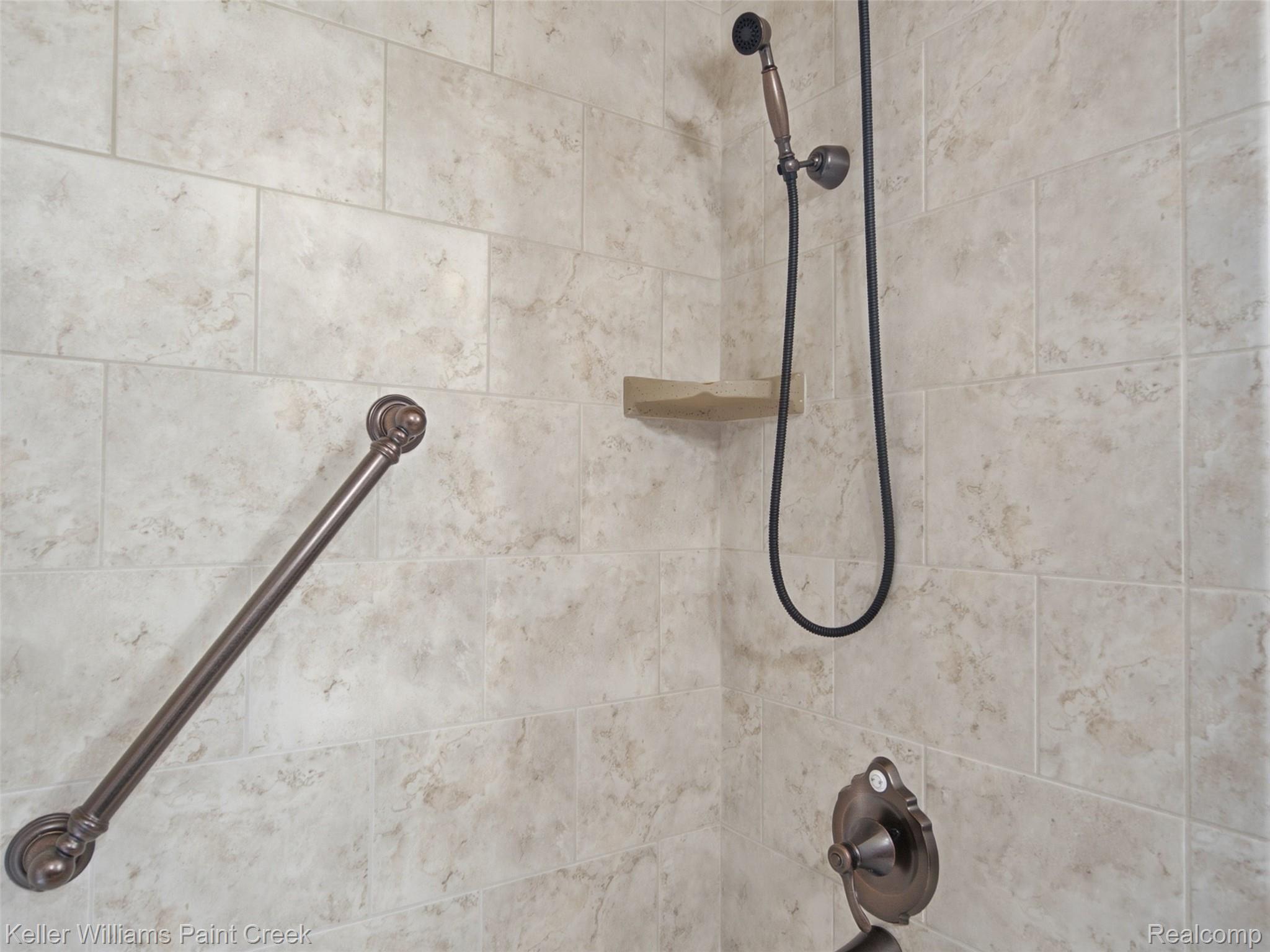 2950 Leyton Court Rochester, MI 48306 - Photo 23 of 46 Tiled shower surround with a built-in shelf, bronze grab bar, and a handheld shower fixture