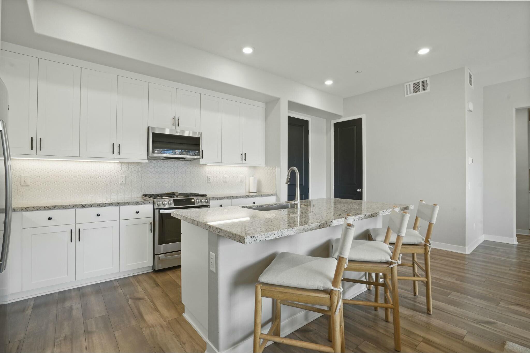 26976 West Prospector Road, Unit 205 Valencia, CA 91381 - Photo 11 of 31 a kitchen with stainless steel appliances granite countertop a stove a sink a refrigerator with a dining table and chairs