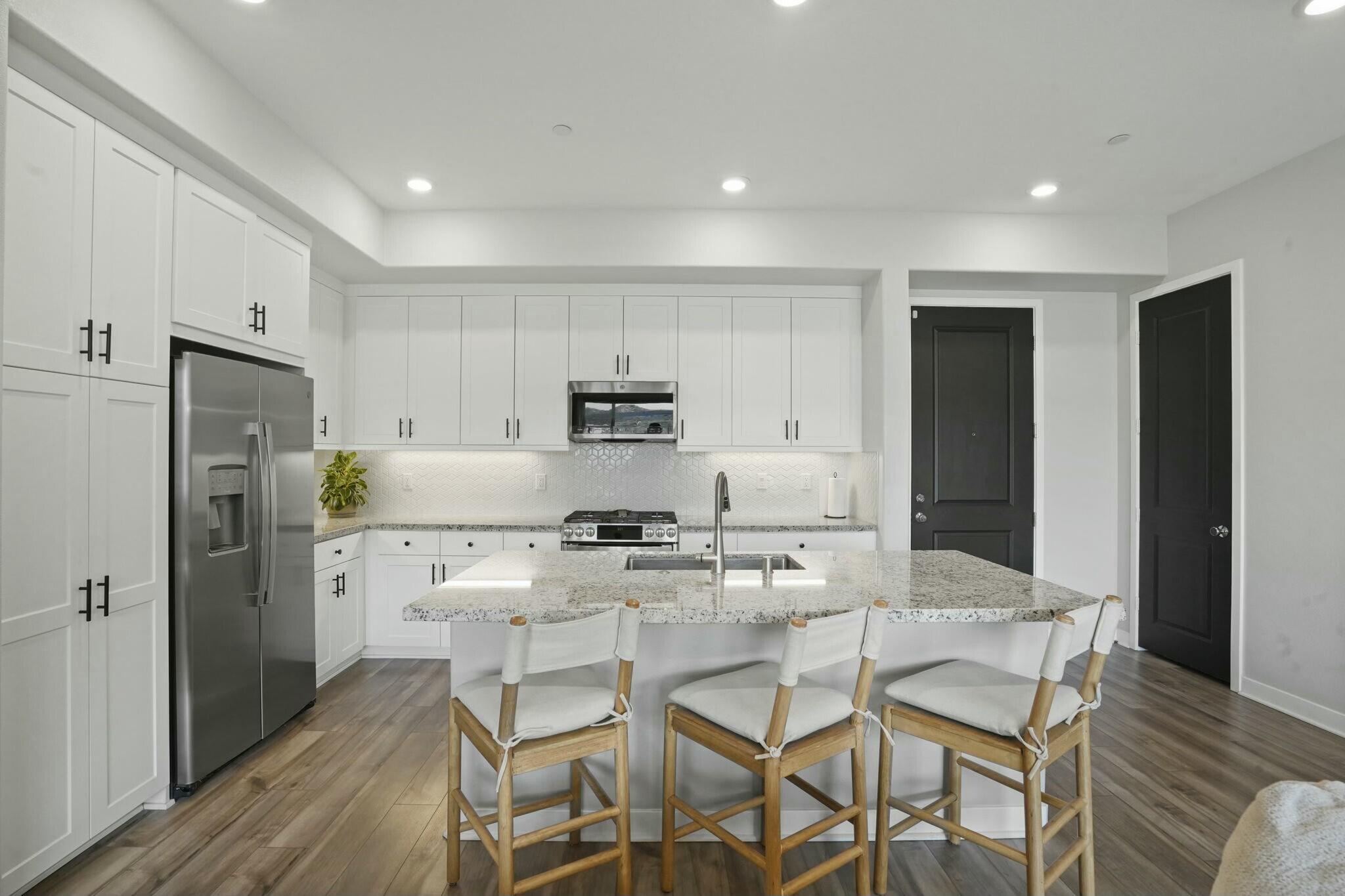 26976 West Prospector Road, Unit 205 Valencia, CA 91381 - Photo 10 of 31 a kitchen with stainless steel appliances a dining table chairs refrigerator and sink