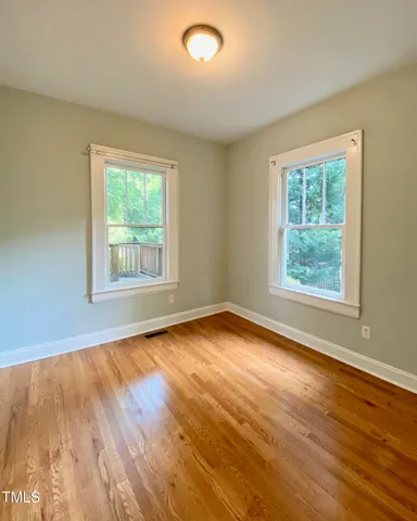 a view of an empty room with wooden floor and a window