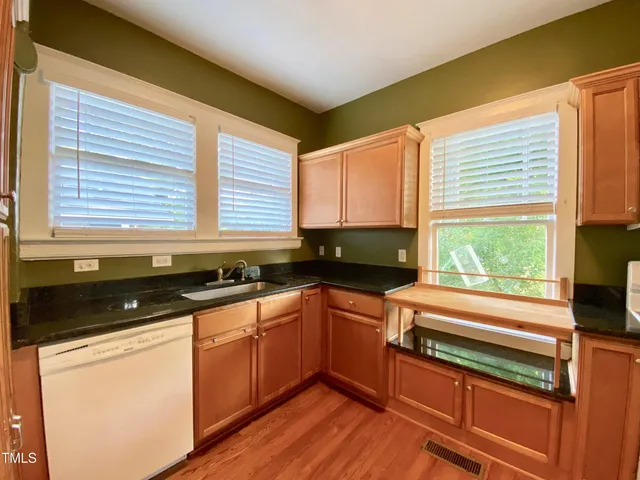a kitchen with granite countertop cabinets stainless steel appliances a sink and a large window