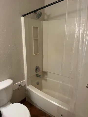 a white toilet sitting next to a bath tub